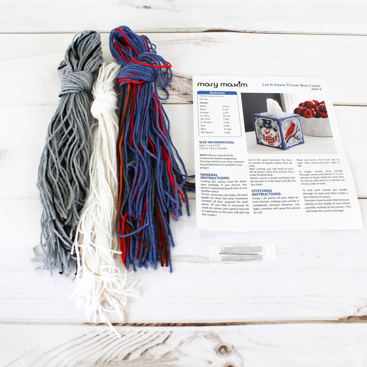 Plastic Canvas Tissue Box Cover with a Snowman in a Top Hat and Scarf, and Cardinal on a branch against a grey snowy background with blue trim.