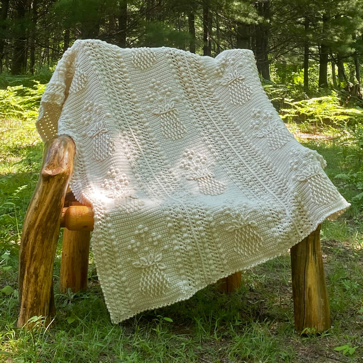 Pineapple and Floral Shoppe Afghan on a wooden chair in the woods
