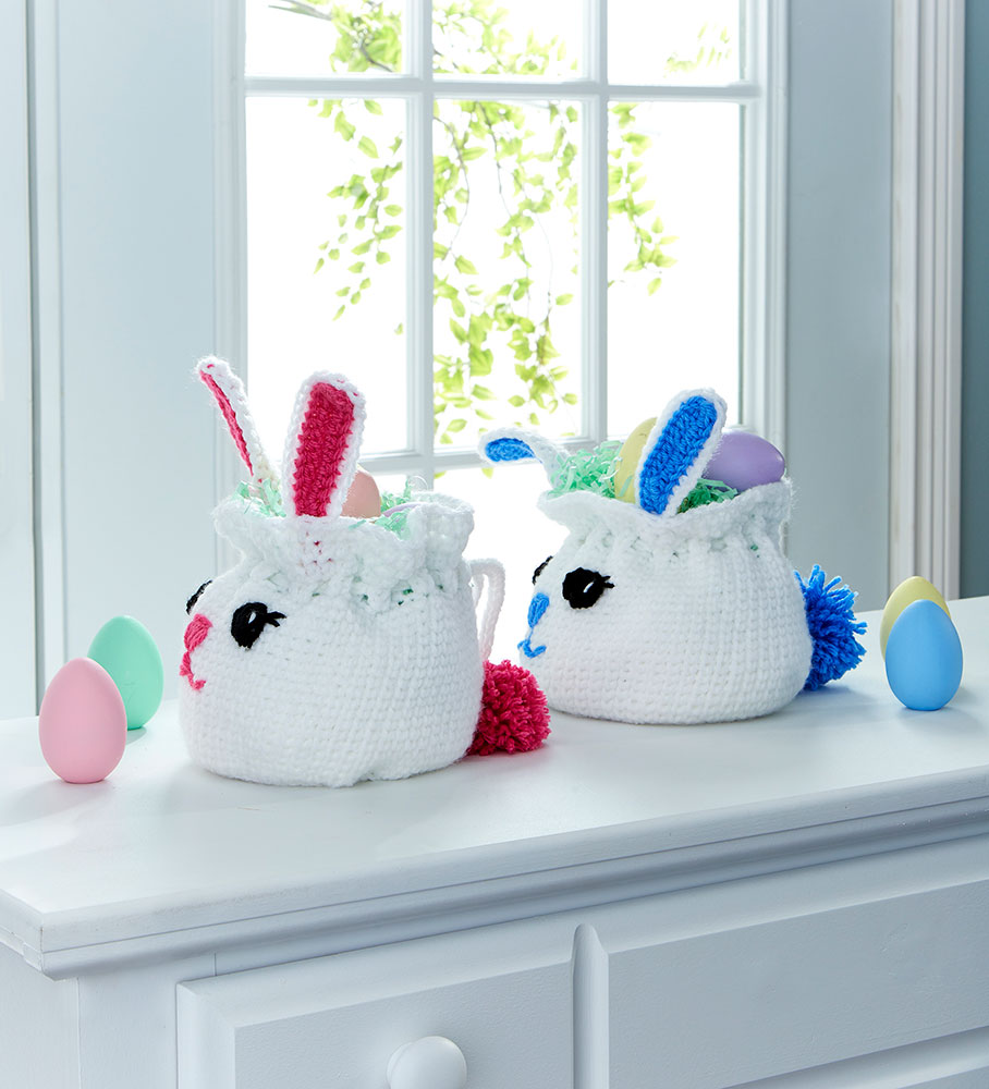 Two Bunny Bag Easter Baskets side view and easter eggs, one with pink ears, nose, and pom pom tail, and one with Blue.