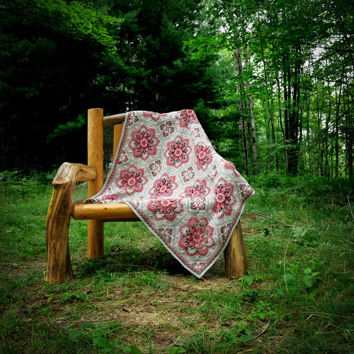 Persian Tiles Afghan in the color Rose Garden laying across a chair in the forest